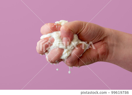 Squeezing mozzarella cheese in one hand, isolated on a purple background. Squeezing mozzarella cheese in one hand, isolated on a purple background. 99619786