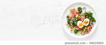 Easter egg salad with prosciutto and broccolini on white background, top view. Easter salad with boiled egg Easter egg salad with prosciutto and broccolini on white background, top view. Easter salad with boiled egg 99620069