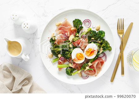 Easter egg salad with prosciutto and broccolini on white background, top view. Easter salad with boiled egg 99620070