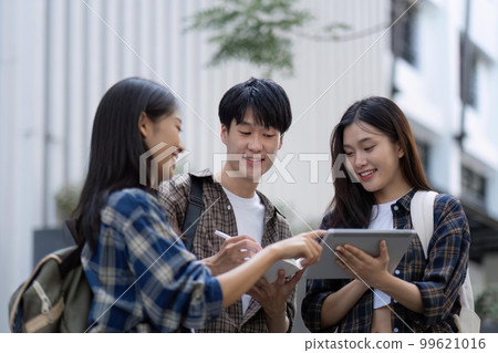 Group of young Asian college students sitting on in front of the school building, talking and focusing on their school project Group of young Asian college students sitting on in front of the school building, talking and focusing on their school project 99621016