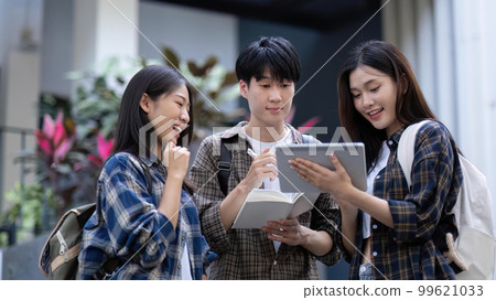 Group of young Asian college students sitting on in front of the school building, talking and focusing on their school project Group of young Asian college students sitting on in front of the school building, talking and focusing on their school project 99621033