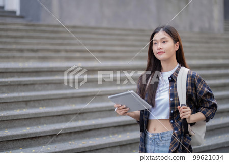 Asian female college student with her laptop in front of the campus building Asian female college student with her laptop in front of the campus building 99621034
