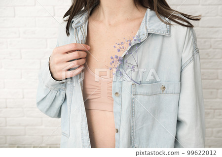 woman wearing denim jacket showing beige bra underwear, dry flowers in a pocket of a jacket. aesthethic natural unretouched skin. woman wearing denim jacket showing beige bra underwear, dry flowers in a pocket of a jacket. aesthethic natural unretouched skin. 99622012