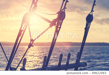 Old wooden pulley block silhouettes at sunset, color toning applied, selective focus. 99622063