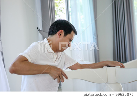 Asian man assembling white table furniture at home Asian man assembling white table furniture at home 99623875
