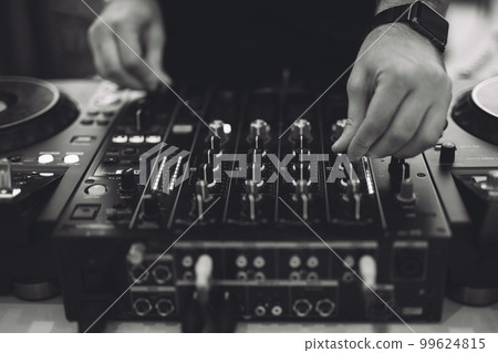 a DJ plays music on a controller at a party. 99624815