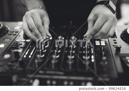 a DJ plays music on a controller at a party. a DJ plays music on a controller at a party. 99624816