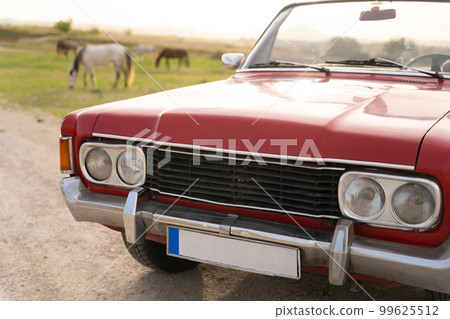 old red cabriolet on the background of horses in the pasture. old red cabriolet on the background of horses in the pasture. 99625512