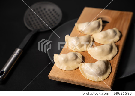 freshly prepared dumplings with kitchen utensils 99625586