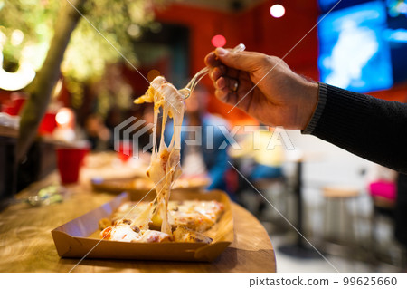 a piece of pizza with melted cheese that stretches 99625660