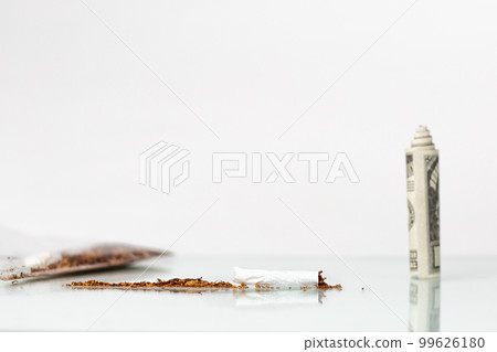 The concept of nicotine dependence and tobacco Smoking. On the glass table is a broken cigarette and standing dollar bill. White background. Copy space 99626180