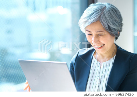 Senior business woman operating a personal computer in the office 99627420