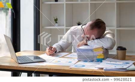 Stressed business man sitting at office workplace. Tired and overworked business man. Young exhausted business men in stress working on laptop computer 99628021
