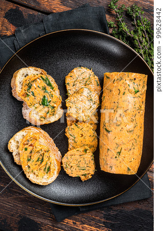 Butter with flavoring additives, sandwich butter with fresh herbs, sweet peppers, lemon, onion, garlic. Wooden background. Top view Butter with flavoring additives, sandwich butter with fresh herbs, sweet peppers, lemon, onion, garlic. Wooden background. Top view 99628442