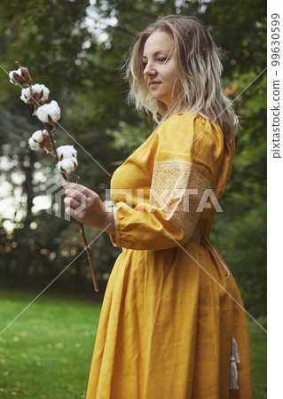 beautiful Ukrainian woman in embroidered dress holds a sprig of cotton 99630599