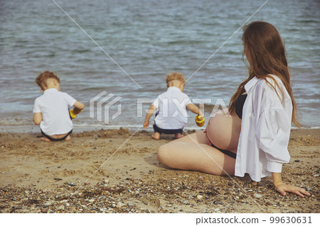 Beautiful pregnant woman looking at her sons playing in the distance 99630631