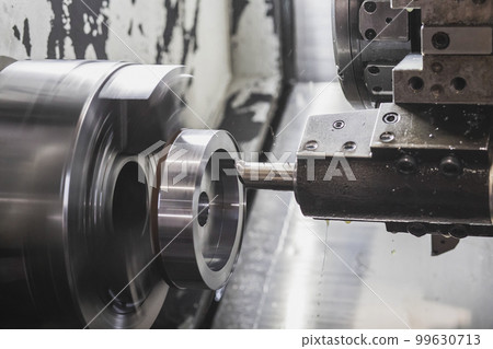 A milling cutter in a CNC machine cuts a metal workpiece that rotates at high speed A milling cutter in a CNC machine cuts a metal workpiece that rotates at high speed 99630713