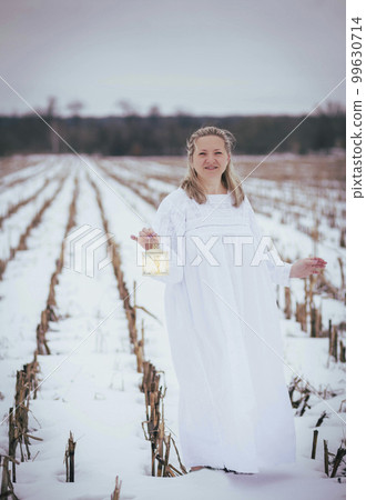 Attractive woman in nightgown in the field in winter with hand lamp Attractive woman in nightgown in the field in winter with hand lamp 99630714