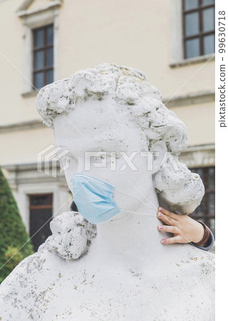 Ancient statue of a woman in a medical mask 99630718