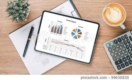 Tablet screen display with charts and reports on office desk workplace. Top view flat lay 99630830