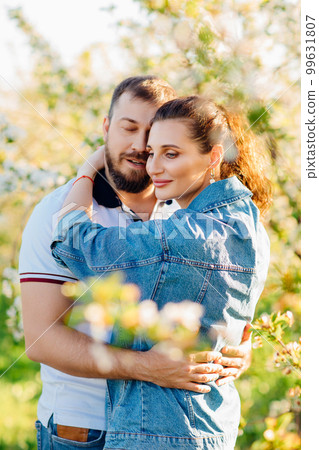 a lovers man and a woman in a blooming spring garden. sunlight. 99631807