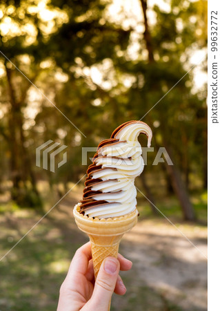 Female hand holding delicious american vanilla chocolate ice cream. Tasty homemade icecream Gelato in the waffle cone. Gluten free vegan dairy free 99632772