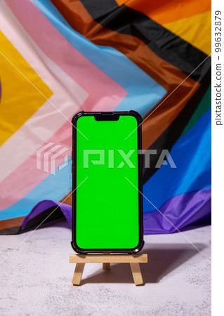 Mobile phone with chroma key on Rainbow LGBTQIA flag made from silk material background. Happy pride month. Symbol of LGBTQ pride month. Equal rights. Peace and freedom. Support LGBTQIA community 99632879