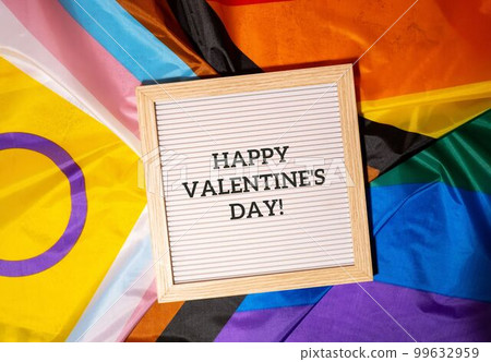HAPPY VALENTINES DAY text frame on Rainbow LGBTQIA flag made from silk material. Symbol of LGBTQ pride month. Equal rights. Peace and freedom. Support LGBTQIA community HAPPY VALENTINES DAY text frame on Rainbow LGBTQIA flag made from silk material. Symbol of LGBTQ pride month. Equal rights. Peace and freedom. Support LGBTQIA community 99632959