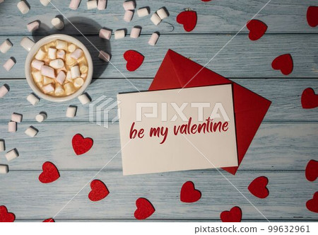 BE MY VALENTINE text Greeting card with red envelope with white cup of coffee and marshmallows on wooden background. Romantic Small hearts Valentine day. Holiday morning BE MY VALENTINE text Greeting card with red envelope with white cup of coffee and marshmallows on wooden background. Romantic Small hearts Valentine day. Holiday morning 99632961