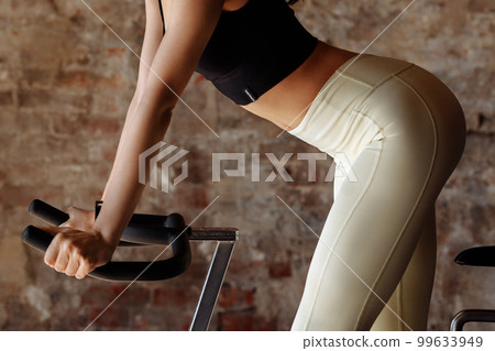 Fitness woman on a bicycle is engaged in spinning in the gym. Fitness woman on a bicycle is engaged in spinning in the gym. 99633949
