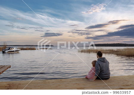 Father and daughter on the shore of the lake watching the sunse Father and daughter on the shore of the lake watching the sunse 99633957