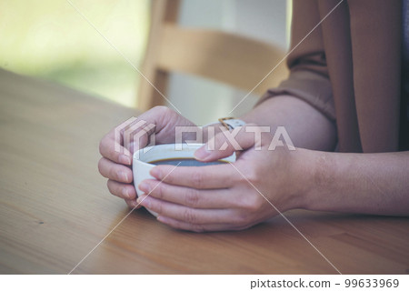 Close up Woman hand holding black coffee cup in green garden cafe. Hands of businesswoman love drinking hot coffee. business women with black coffee or hot chocolate in coffee shop. Caffeine drinking Close up Woman hand holding black coffee cup in green garden cafe. Hands of businesswoman love drinking hot coffee. business women with black coffee or hot chocolate in coffee shop. Caffeine drinking 99633969
