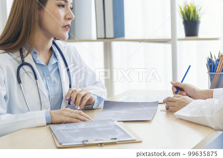 Two asian women hand doctors meeting write prescription medical clinic. Doctor discuss using laptop write note. Close up hands of two women doctor medical lab discussing together healthcare teamwork 99635875