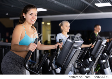 Young girl working out on elliptical machine in gym 99636140