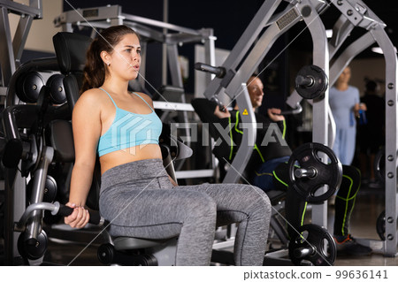 Sporty young woman using arm extension machine in gym 99636141