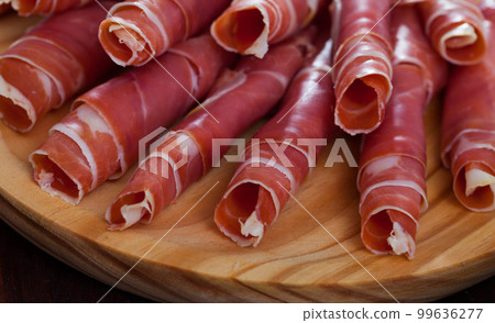 Spanish dry cured jamon on wooden plate 99636277