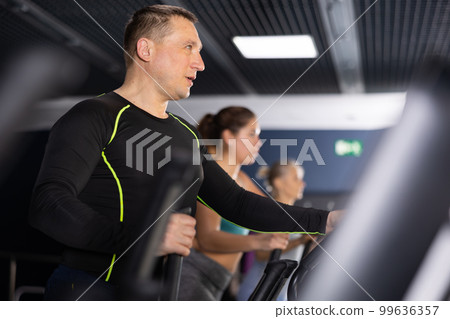 Middle aged man in the gym is engaged in sports using an ellipsoid simulator. Healthy lifestyle and sport concept 99636357