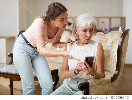Mother and daughter using smartphone together at home Mother and daughter using smartphone together at home 99636643