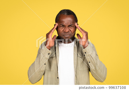 Sad adult black man in casual presses his hands to temples, suffers from headache and migraine 99637108