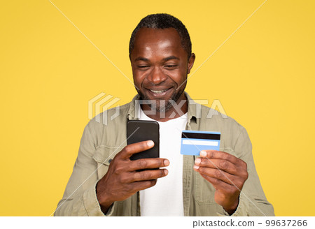 Happy mature black male in casual using phone and credit card, enjoy sale remotely 99637266