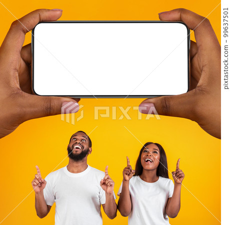 Happy Black Couple Pointing At Big Blank Smartphone In Giant Female Hands Happy Black Couple Pointing At Big Blank Smartphone In Giant Female Hands 99637501
