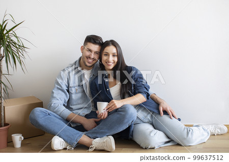 Beautiful Young Couple Relaxing On Floor After Relocation To New Home 99637512