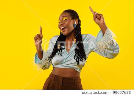 Black Female Listening To Music Via Earbuds Over Yellow Background Black Female Listening To Music Via Earbuds Over Yellow Background 99637628
