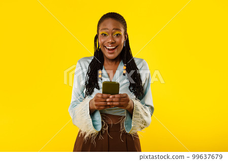 Excited Black Woman Using Cellphone Advertising App On Yellow Background 99637679