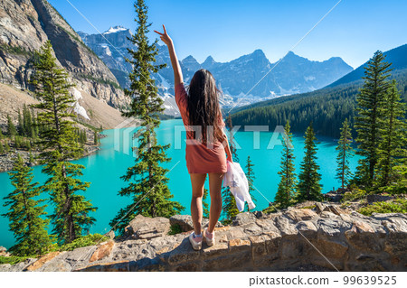 Young girl enjoying Moraine Lake beautiful scenery. Banff National Park nature landscape. Canadian Rockies summer time. Alberta, Canada. Young girl enjoying Moraine Lake beautiful scenery. Banff National Park nature landscape. Canadian Rockies summer time. Alberta, Canada. 99639525