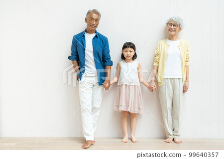 Senior couple holding hands and grandchild girl 99640357