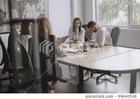 People are working on the project. Men and women in suits sitting at the table. Businessmen use a laptop. People are working on the project. Men and women in suits sitting at the table. Businessmen use a laptop. 99640548
