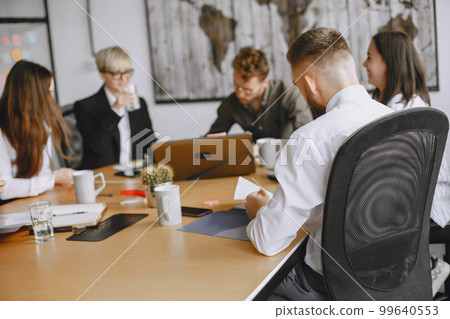 People are working on the project. Men and women in suits sitting at the table. Businessmen use a laptop. 99640553