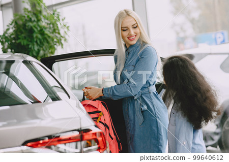 Family in a car salon. Woman buying the car. Little african girl with mther. 99640612