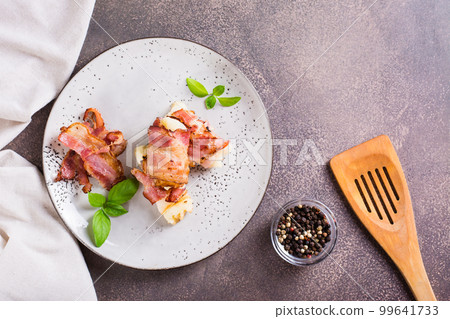 Mashed potatoes wrapped in fried bacon on a plate on the table. Top view Mashed potatoes wrapped in fried bacon on a plate on the table. Top view 99641733